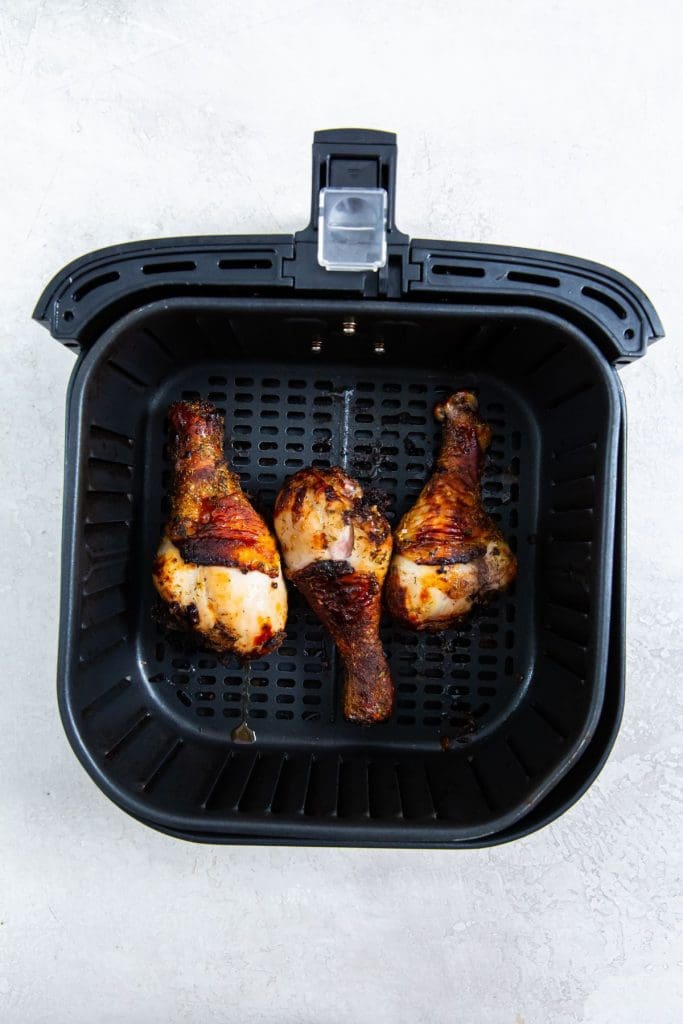 black air fryer with cooked chicken inside