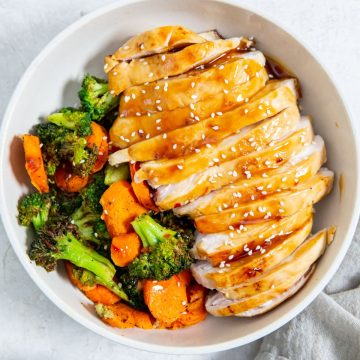 white bowl with chicken veggies and rice inside. gray towel next to it