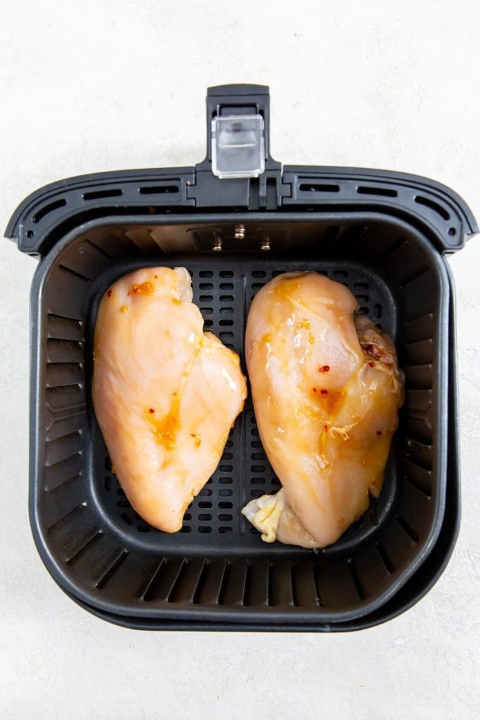 black air fryer with raw chicken inside