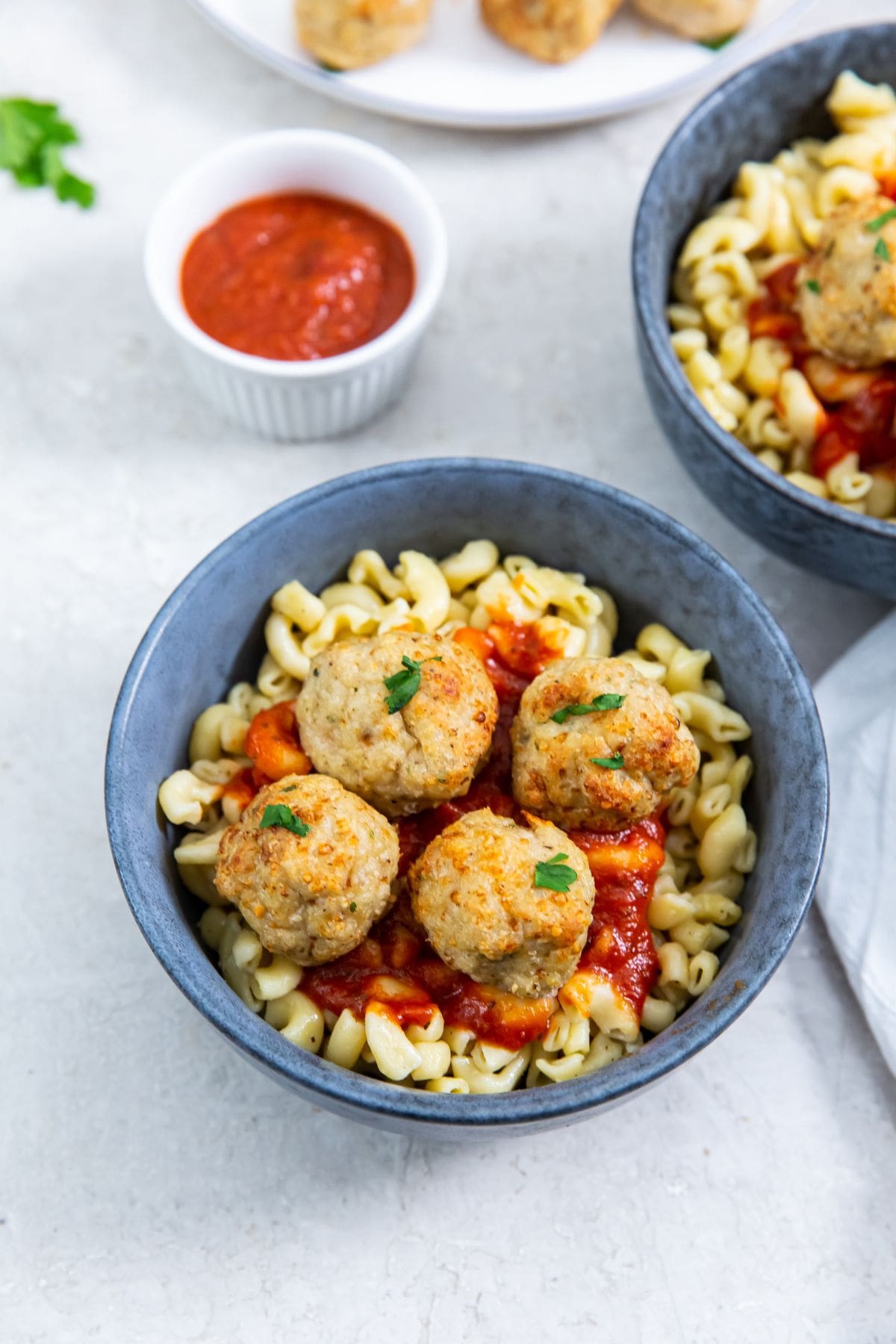 blue bowls with pasta and meatballs on top. sauce inn the back