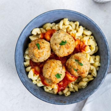 blue bowls with pasta and meatballs on top. sauce inn the back