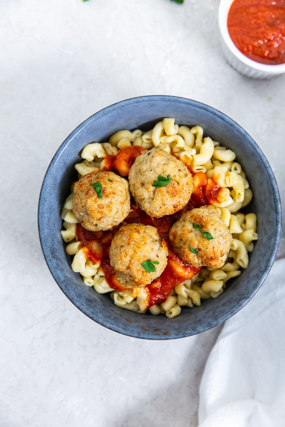 blue bowls with pasta and meatballs on top. sauce inn the back