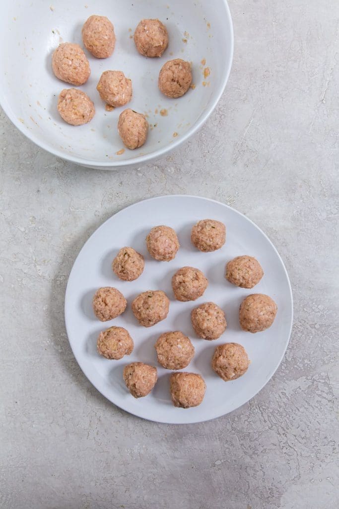 two white plates with chicken meatballs into balls