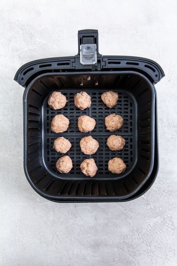 black air fryer with raw ground chicken inside