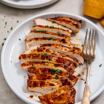 white plate with a chicken cut-up fork on the plate. orange towel