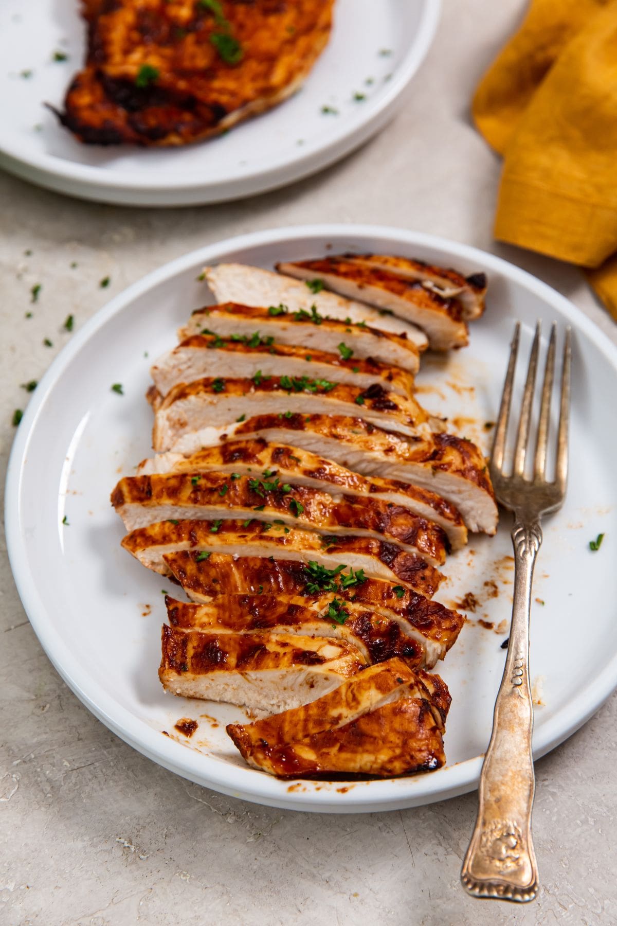 white plate with a chicken cut-up fork on the plate. orange towel