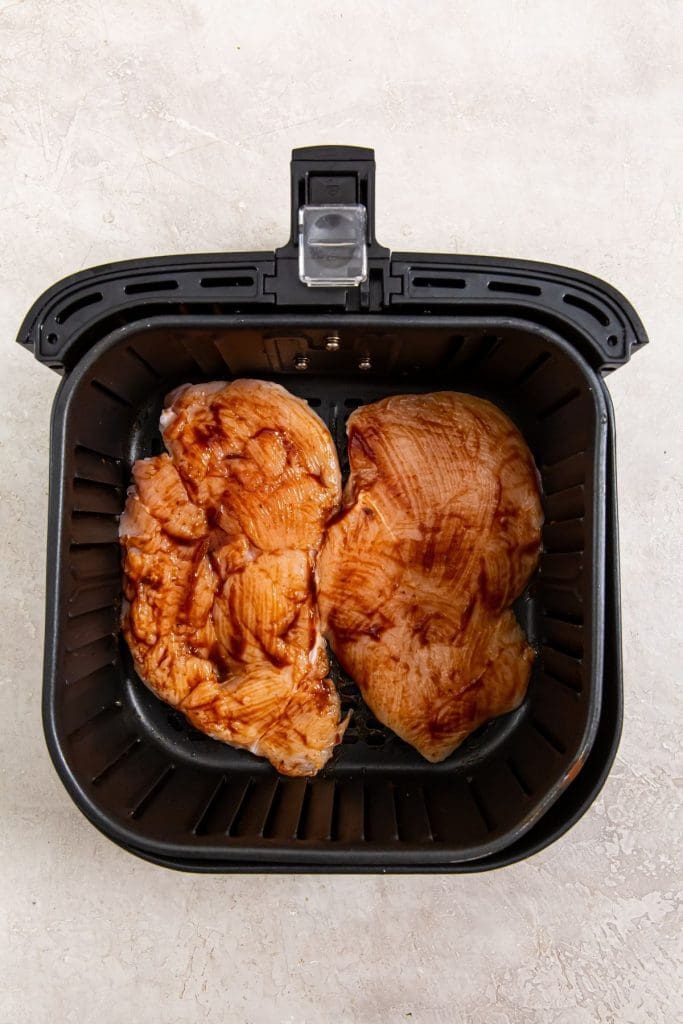 black air fryer basket with raw chicken inside