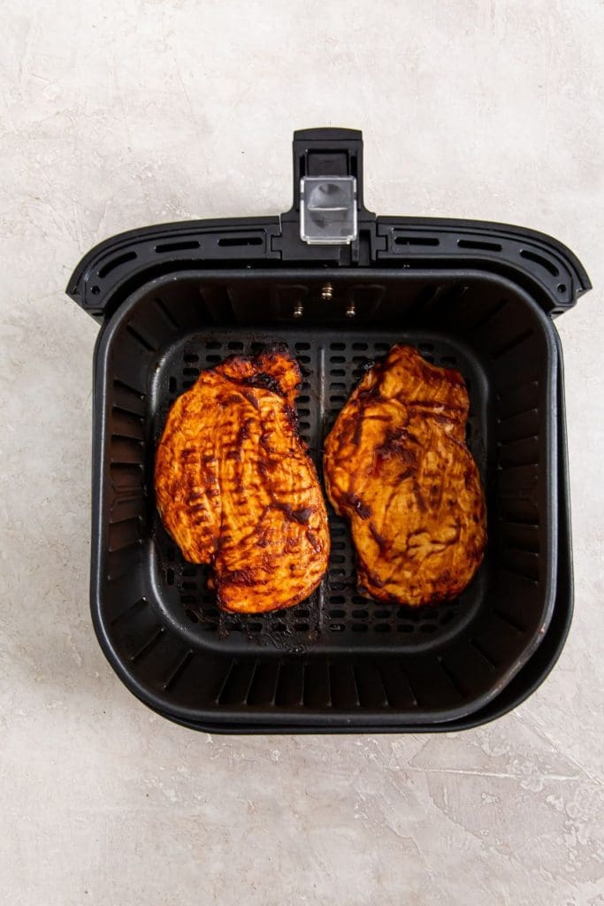 black air fryer basket with cooked chicken inside