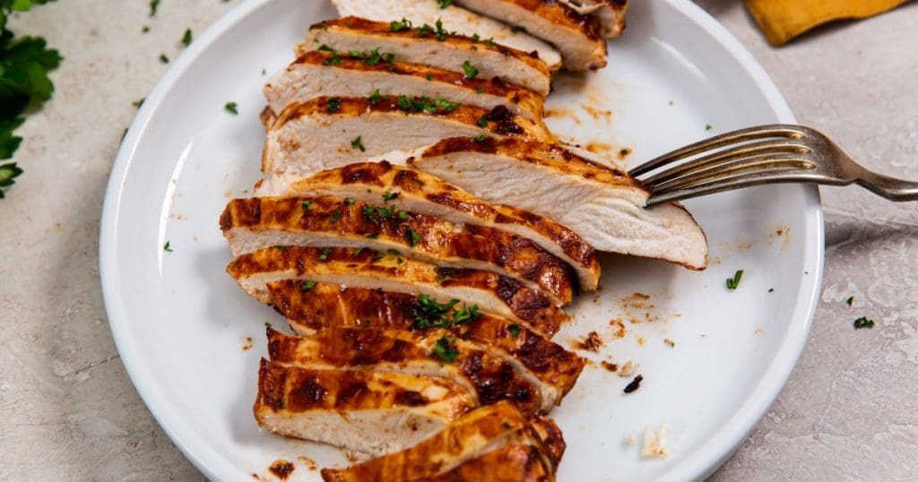 white plate with a chicken cut-up fork on the plate. orange towel