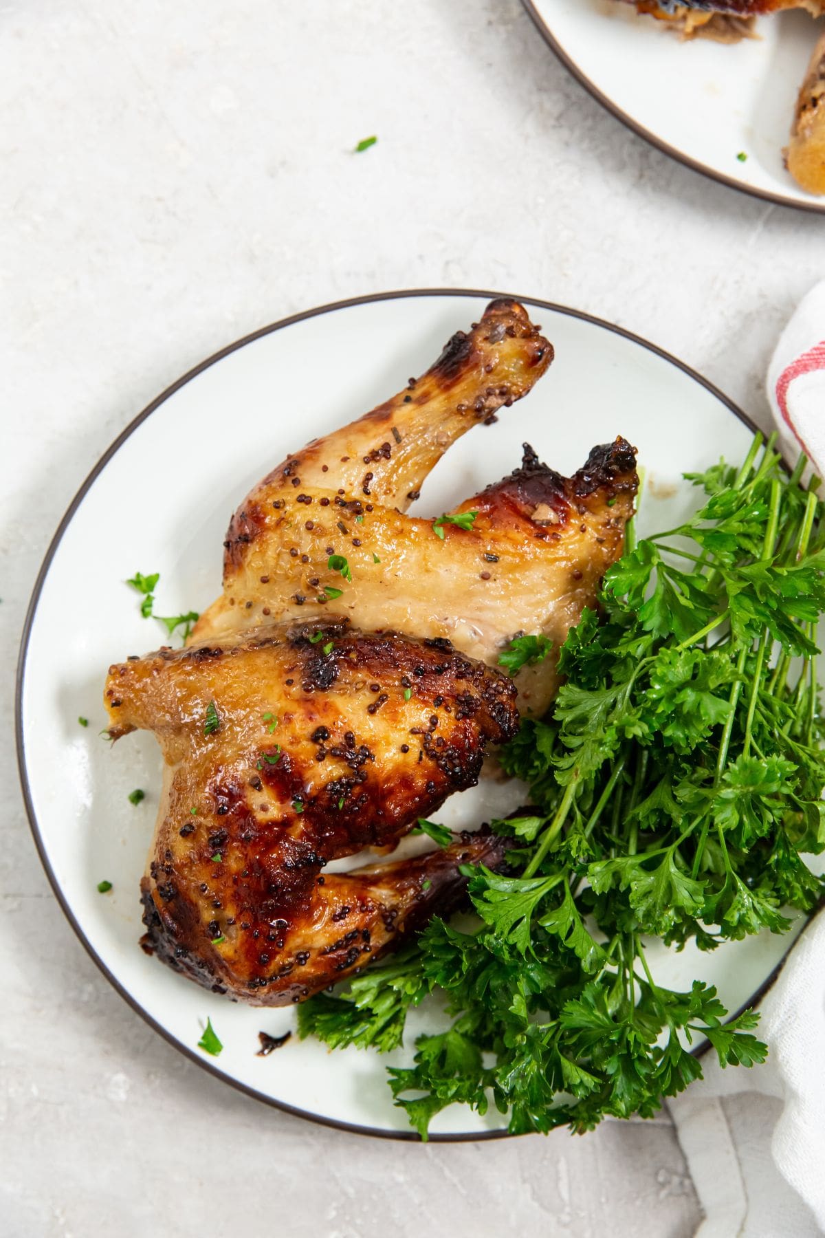 chicken cut with parsley on a white plate. white and pink towel next to it