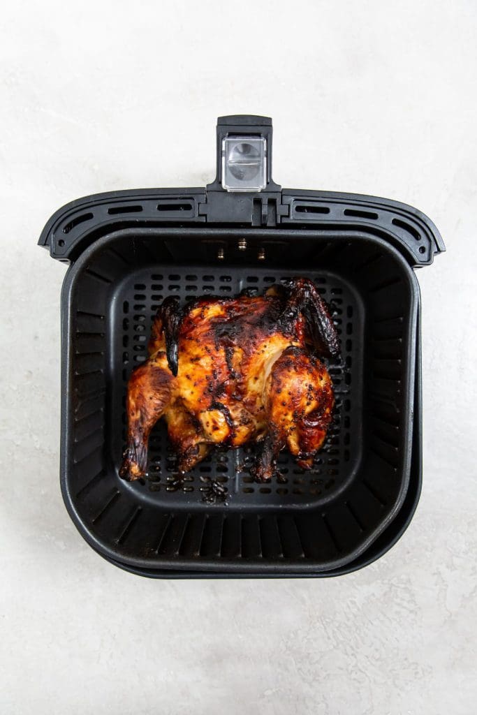 cooked chicken inside a black air fryer basket