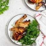 chicken cut with parsley on a white plate. white and pink towel next to it