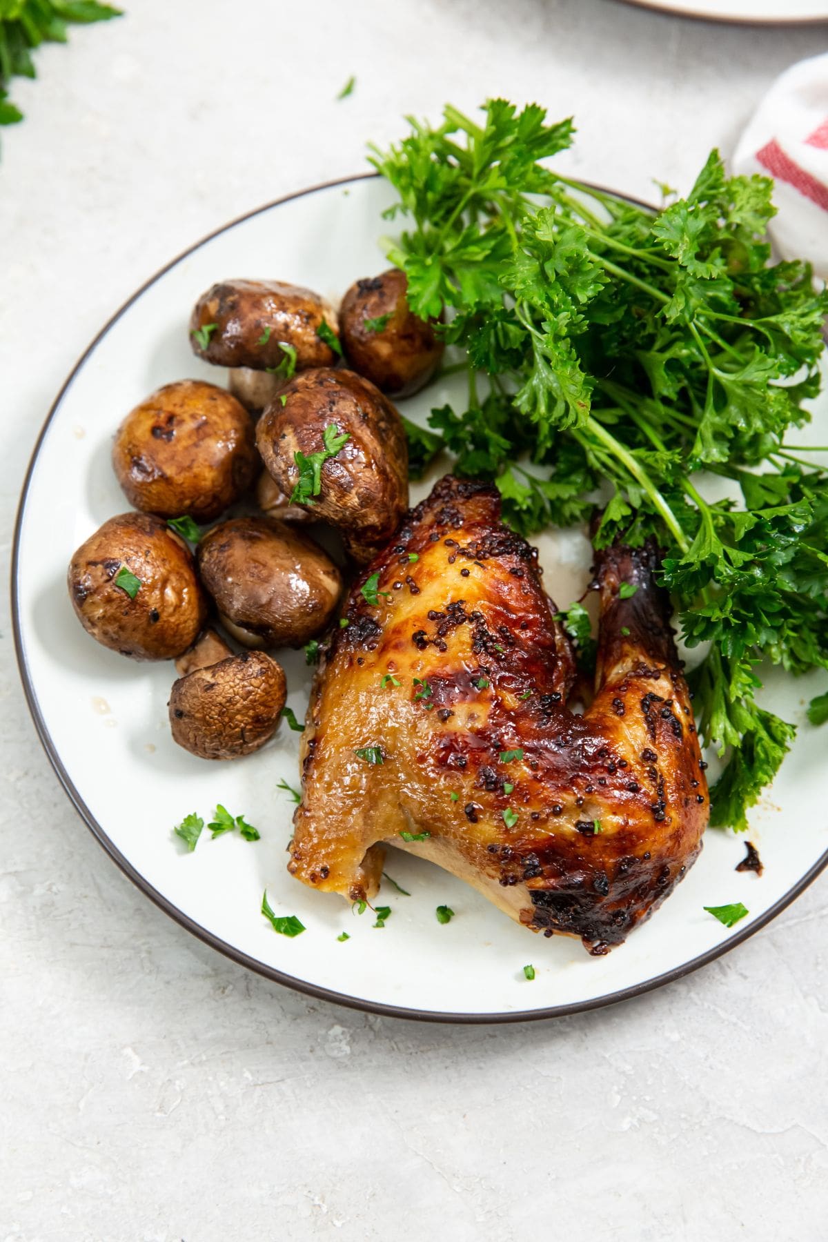 chicken cut with parsley and mushrooms on a white plate. white and pink towel next to it