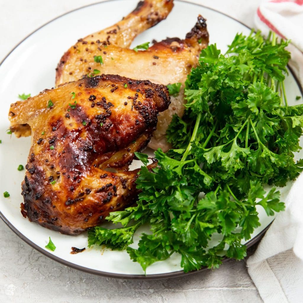 chicken cut with parsley on a white plate. white and pink towel next to it