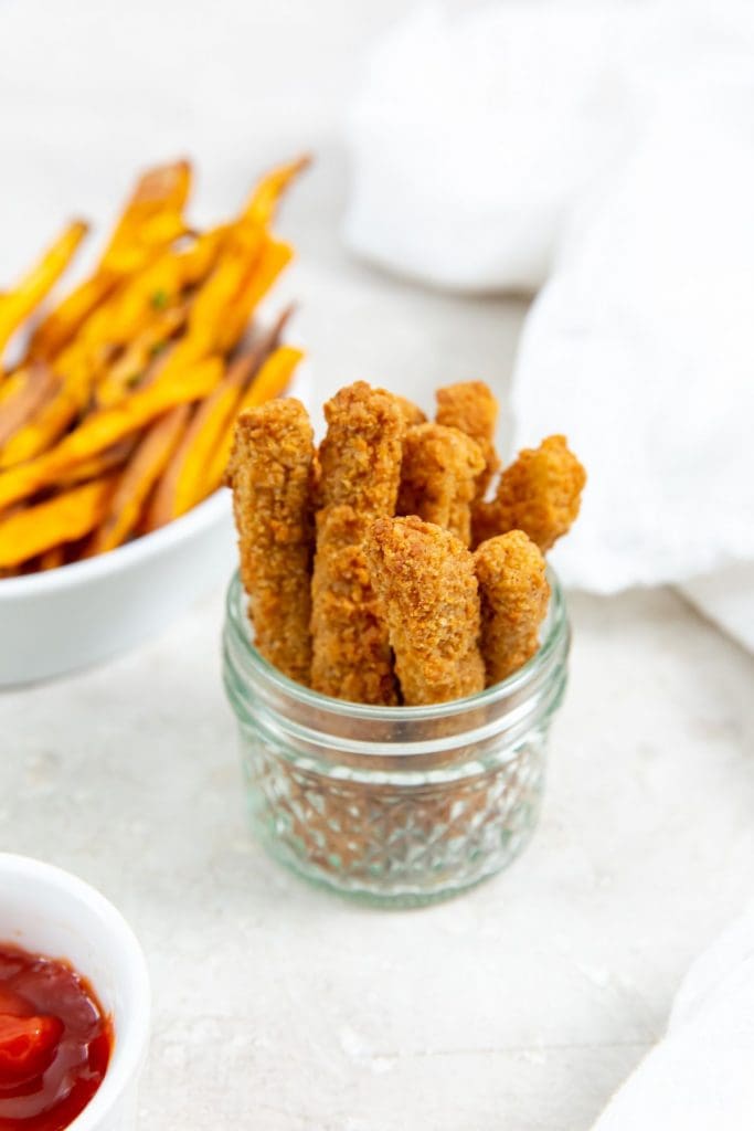 chicken fries inside a mason jar ketchup up front and sweet potatoes in the back. white towel next to it