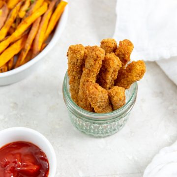 chicken fries inside a mason jar ketchup up front and sweet potatoes in the back. white towel next to it