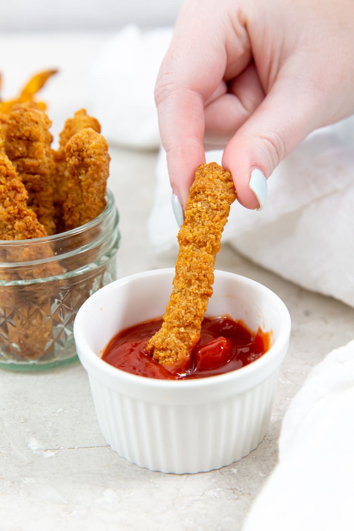 chicken fries dunk in ketchup. chicken fries and sweet potato fries in the background