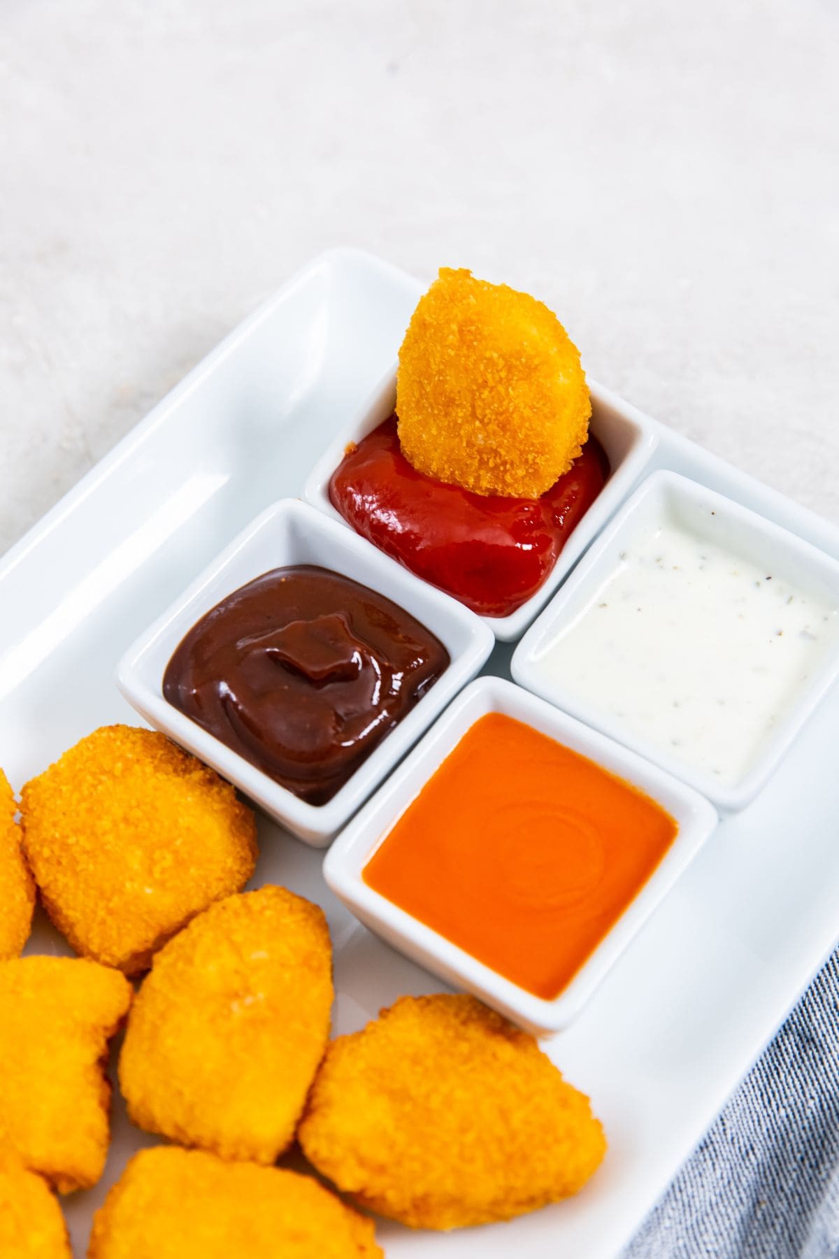 white plate with chicken nuggets on it. one dipped in ketchup