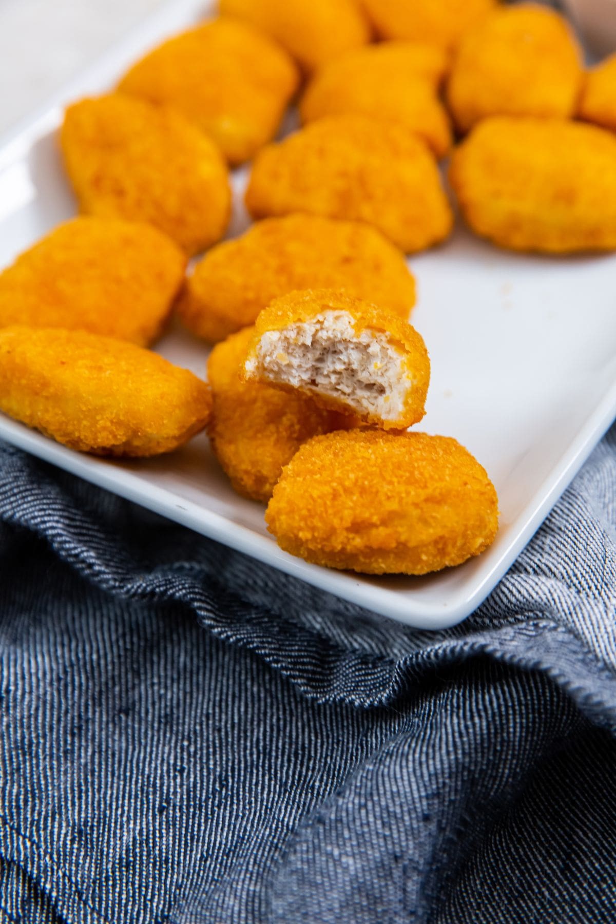 white plate with chicken nuggets one nugget has a bite out of it.