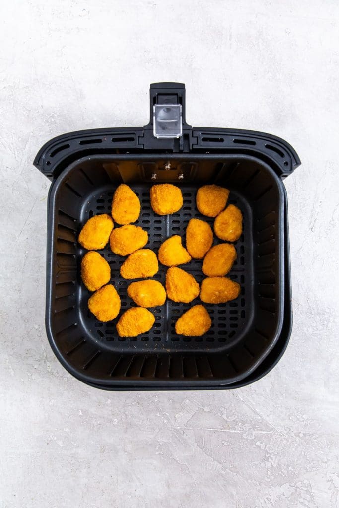 black air fryer with frozen nuggets inside