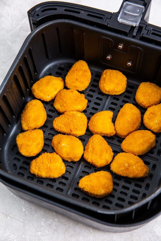 black air fryer with cooked nuggets inside