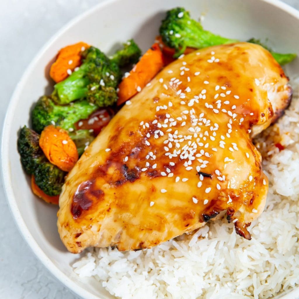 white bowl with chicken veggies and rice inside. gray towel next to it