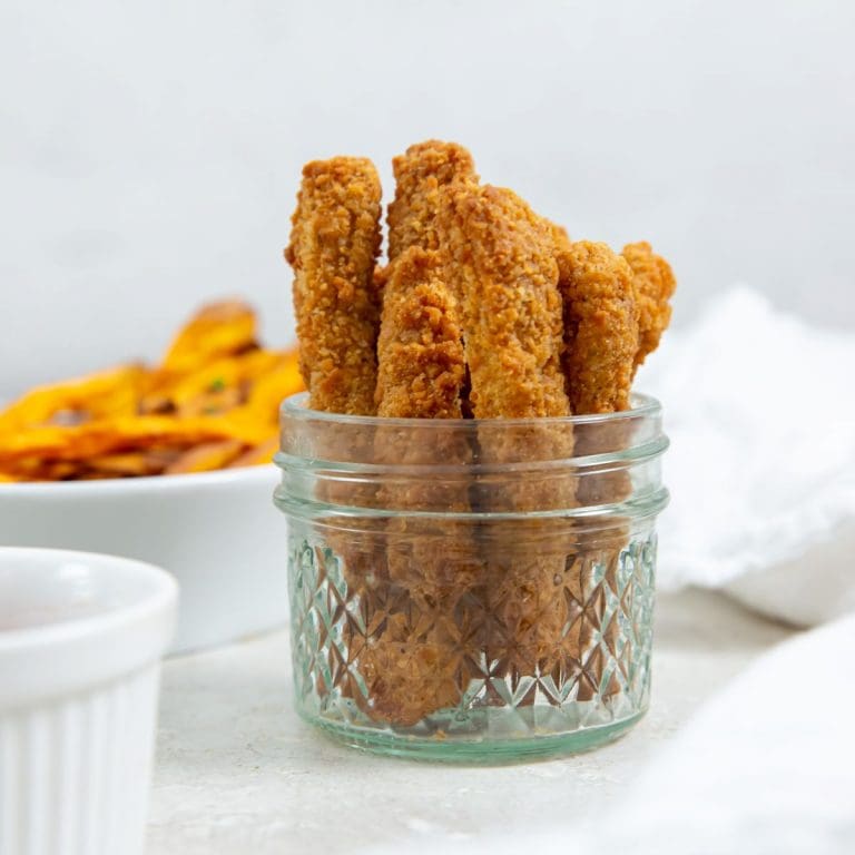 chicken fries inside a mason jar ketchup up front and sweet potatoes in the back. white towel next to it