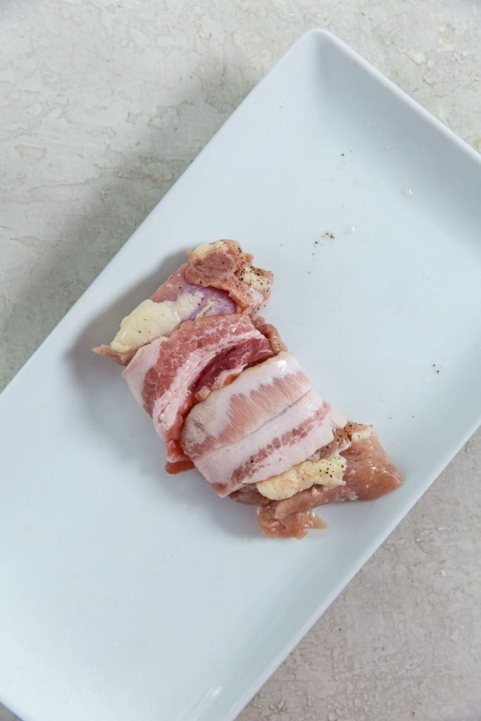 one chicken wrapped in bacon on a white plate