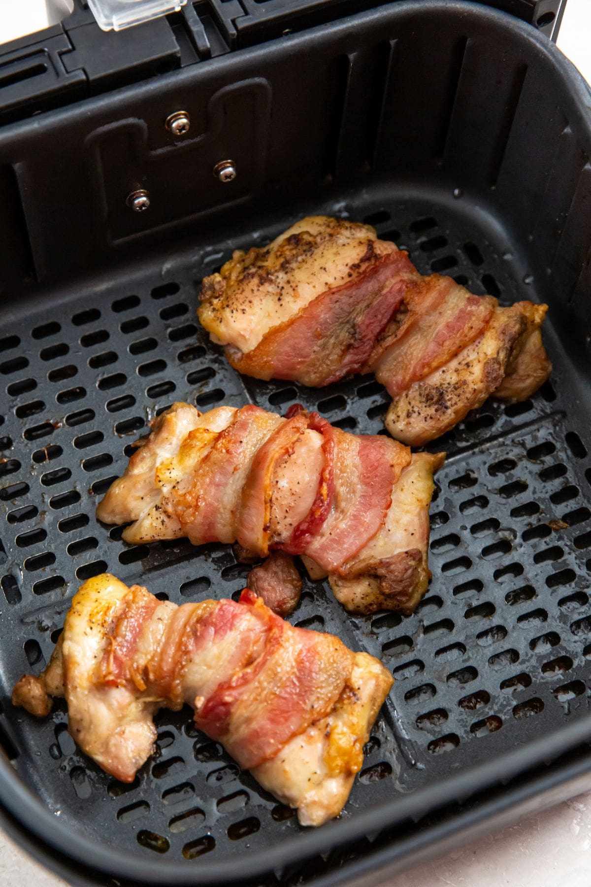 black air fryer with cooked chicken inside