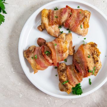 white plate with chicken on it parsley spindled on top. white towel and parsley on top.