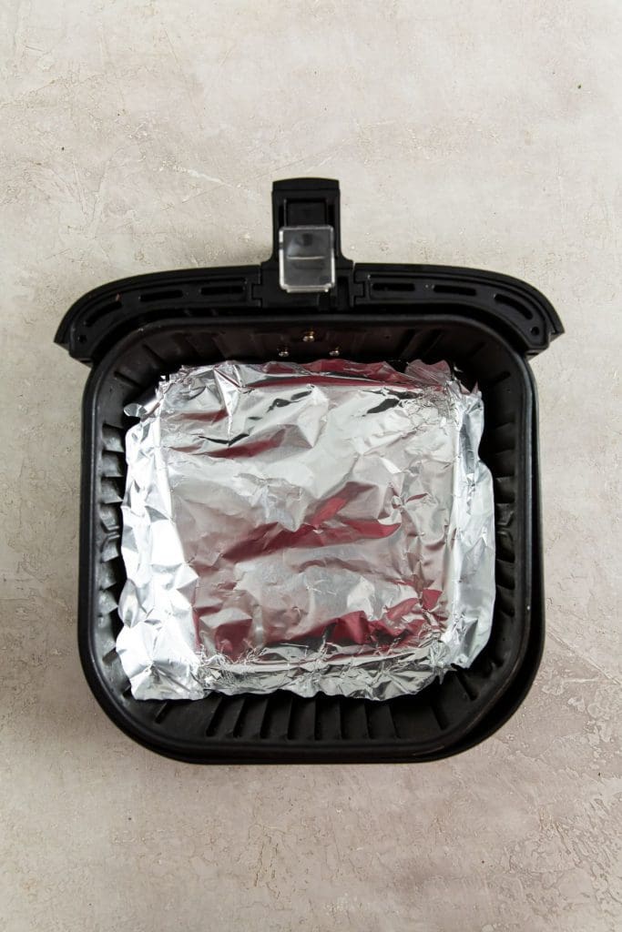 black air fryer basket with aluminum foil inside