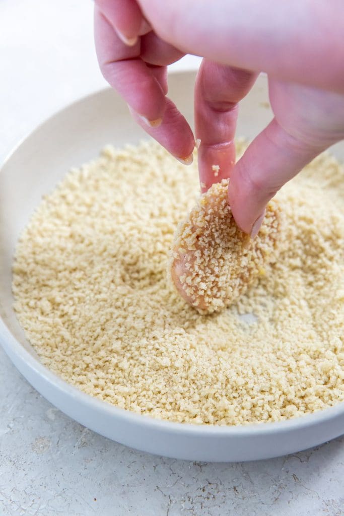 bowl of bread crumbs with chicken dunked in bread crumbs