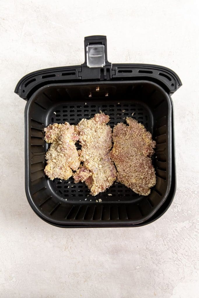 black air fryer basket with raw chicken inside