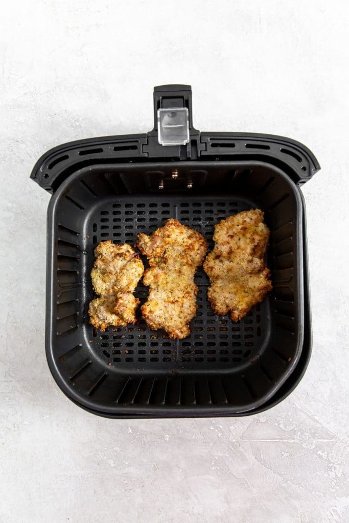 black air fryer basket with cooked chicken inside