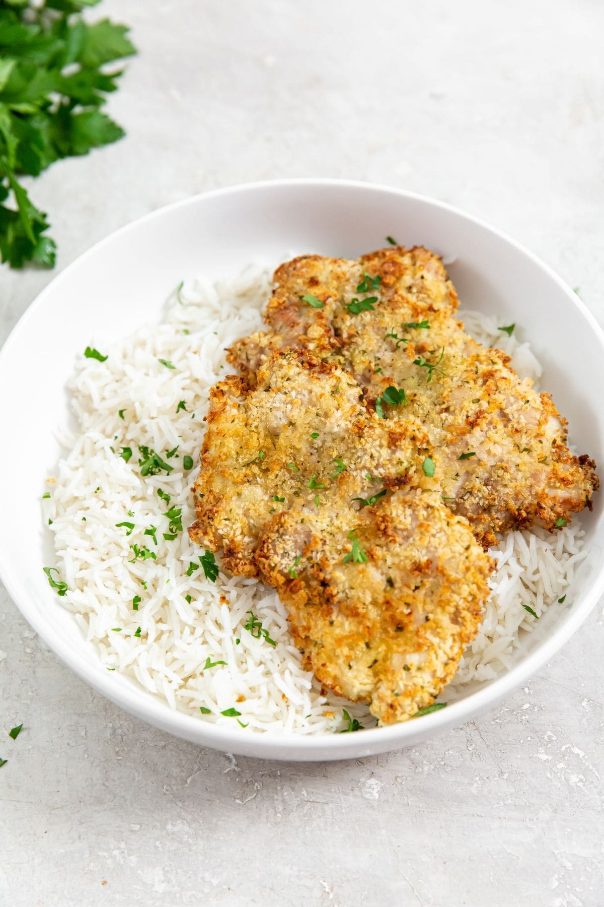 chicken and rice in a white bowl. parsley and white towel in the back