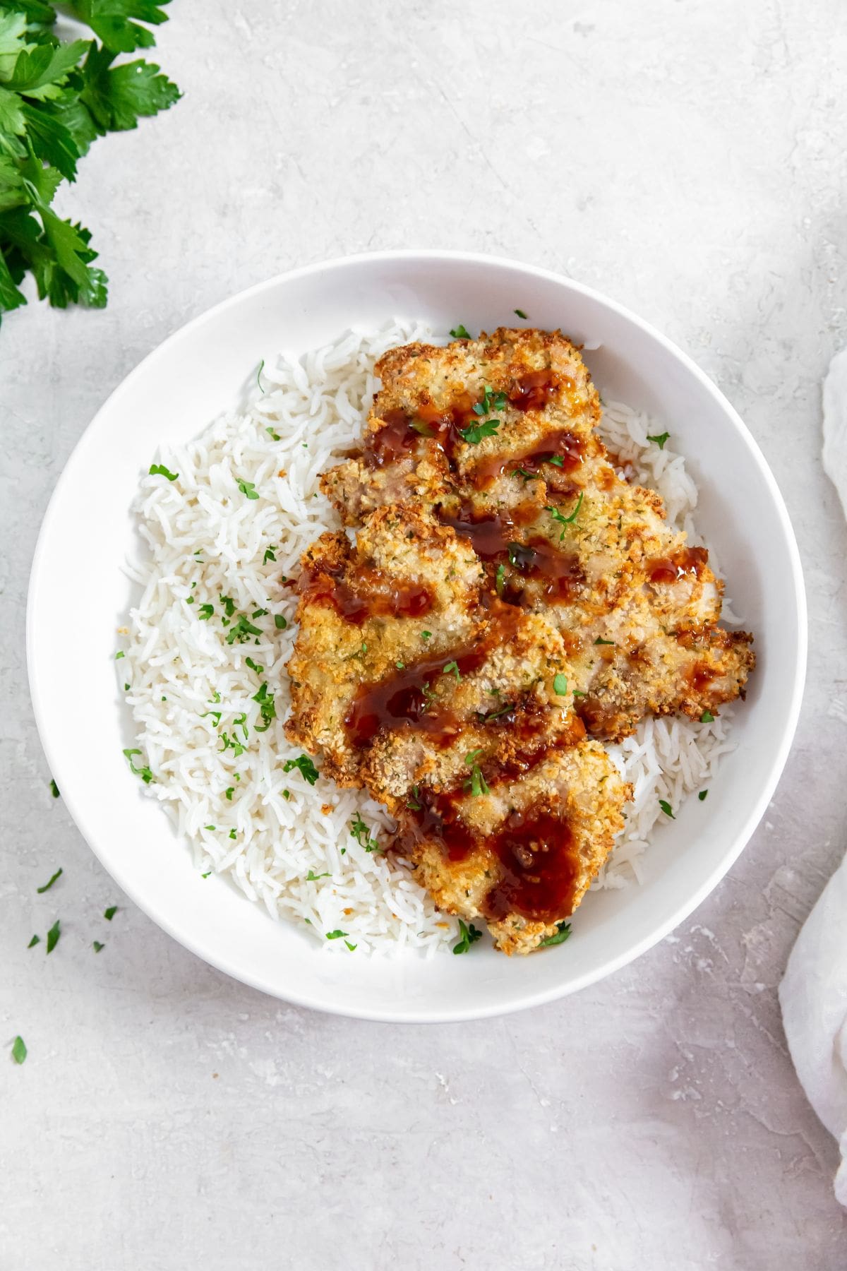 chicken and rice in a white bowl. parsley and white towel in the back