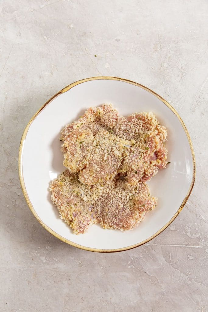 glass bowl with chicken all coated in bread crumbs