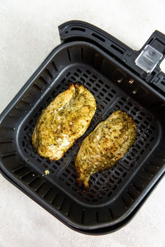 black air fryer with cooked chicken inside