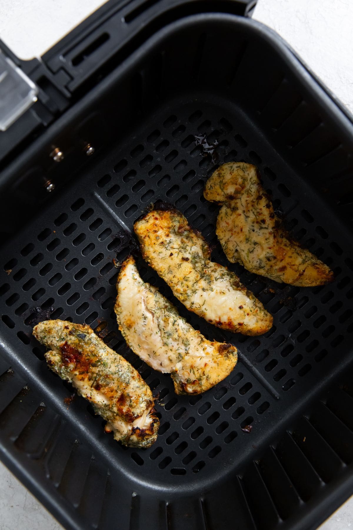 black air fryer with cooked chicken inside