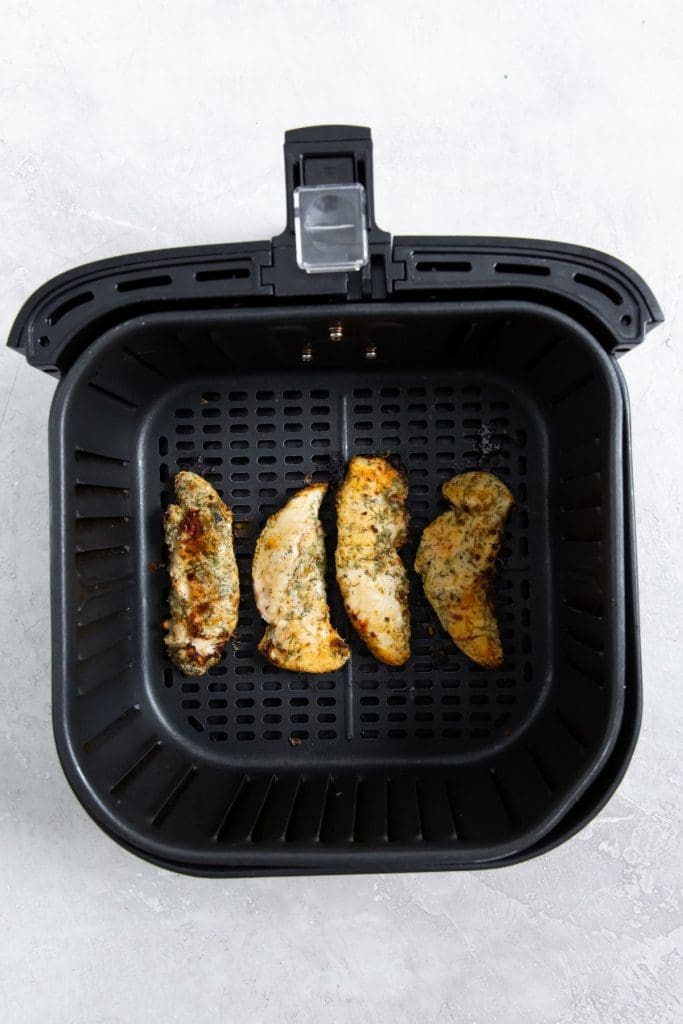 black air fryer basket with cooked chicken inside