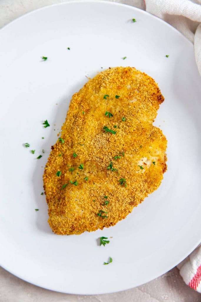 white plate with chicken and parsley on top