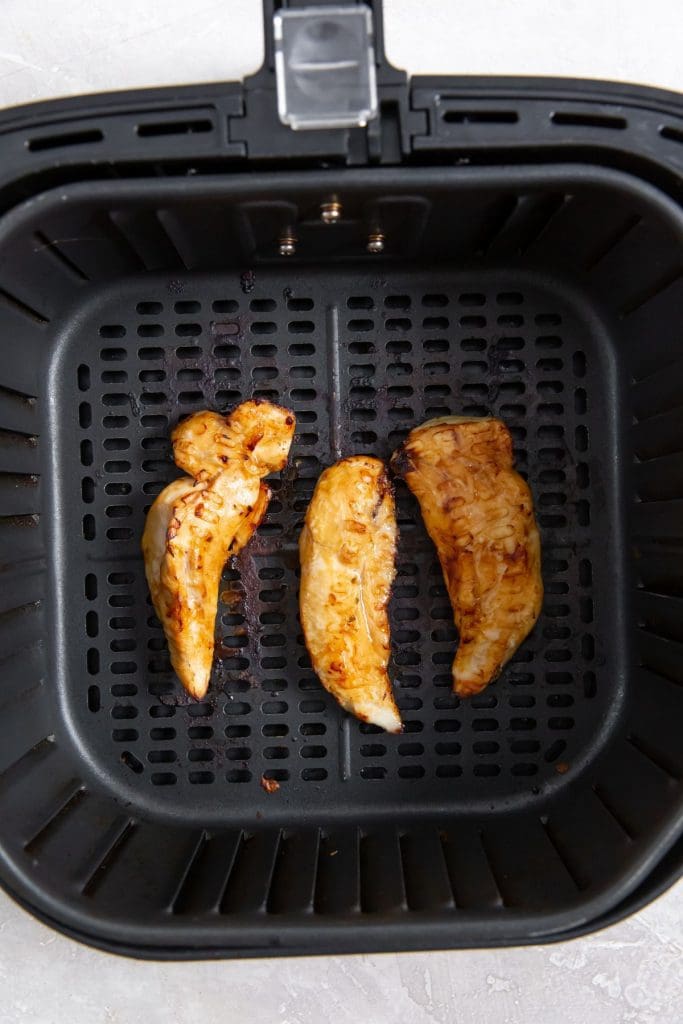 black air fryer with cooked chicken inside