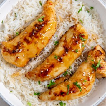 white bowl with chicken and rice parsley and towel in the back