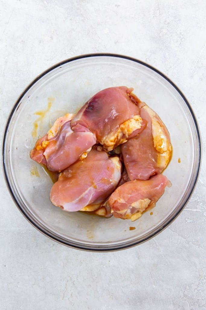 glass bowl with chicken coated in sauce