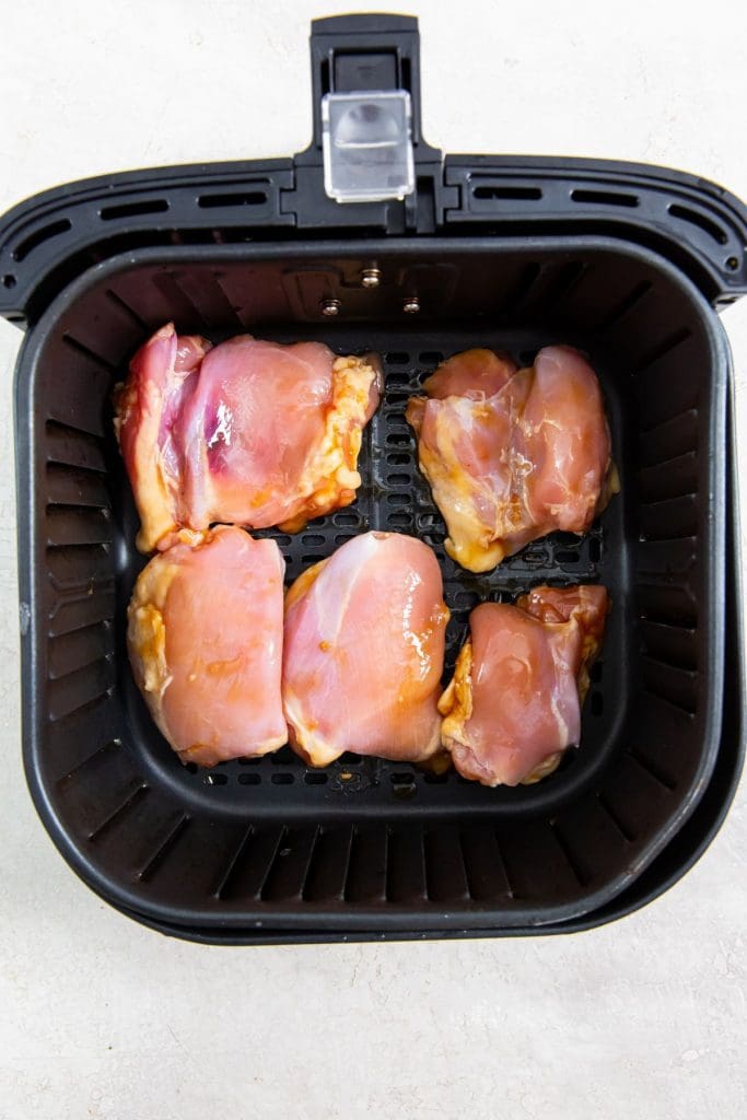 black air fryer with raw chicken inside