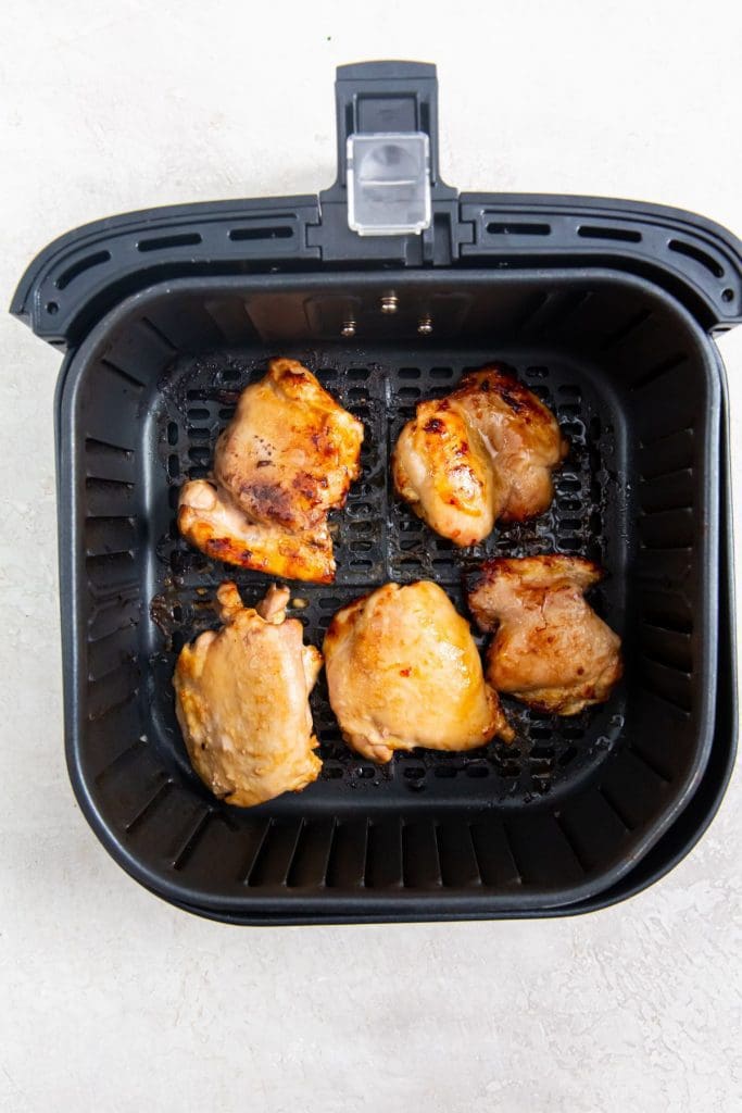 black air fryer with cooked chicken inside