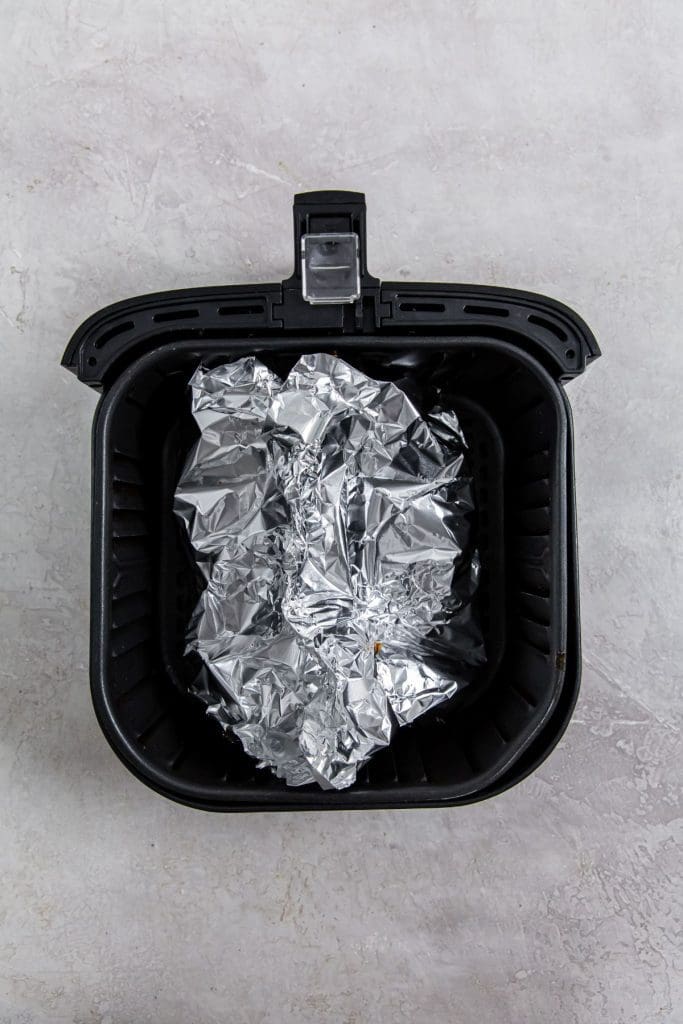 black air fryer with aluminum foil inside