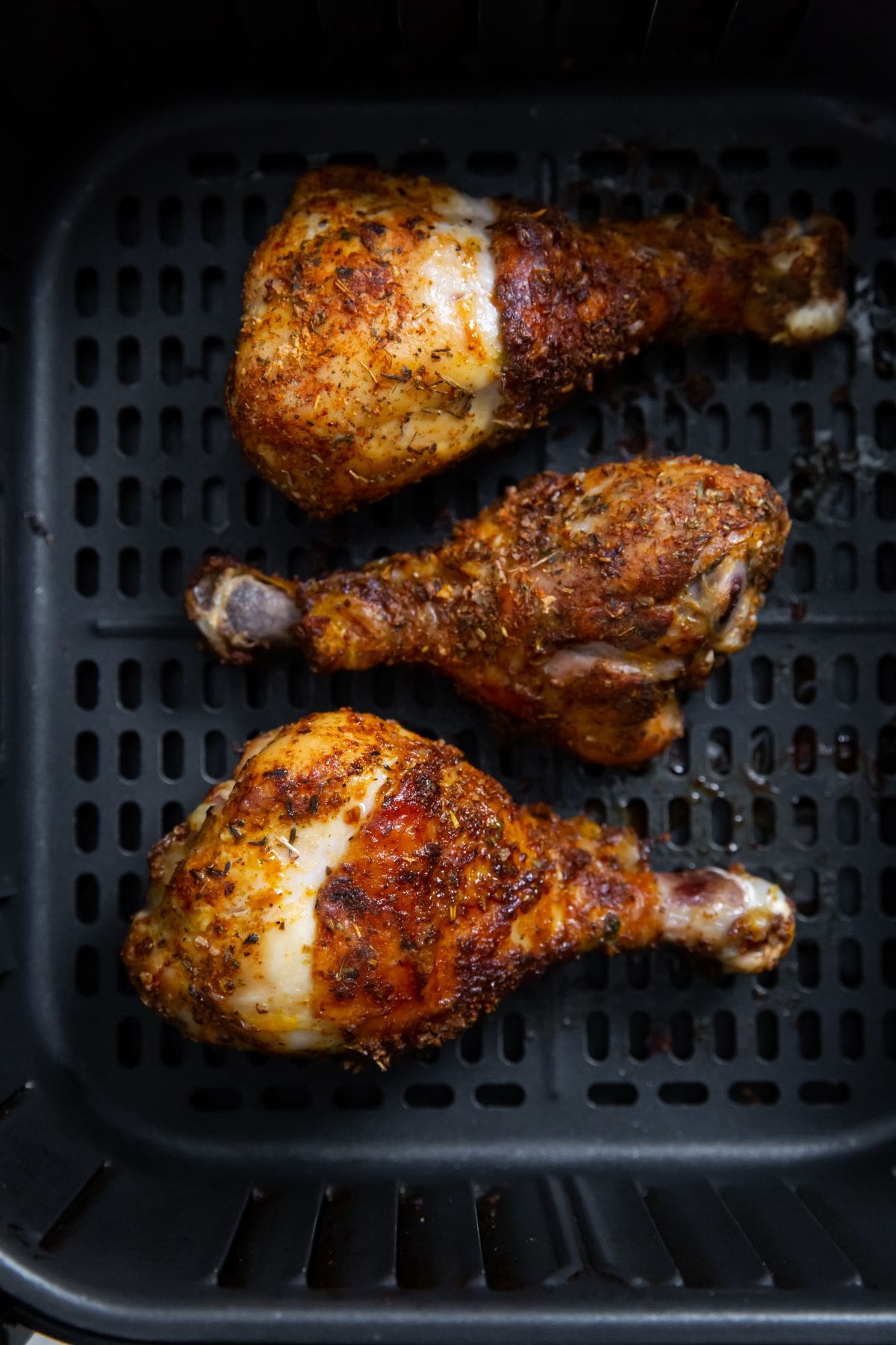 black air fryer with cooked chicken inside