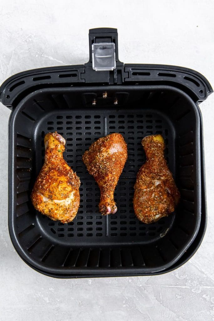 black air fryer with cooked chicken inside