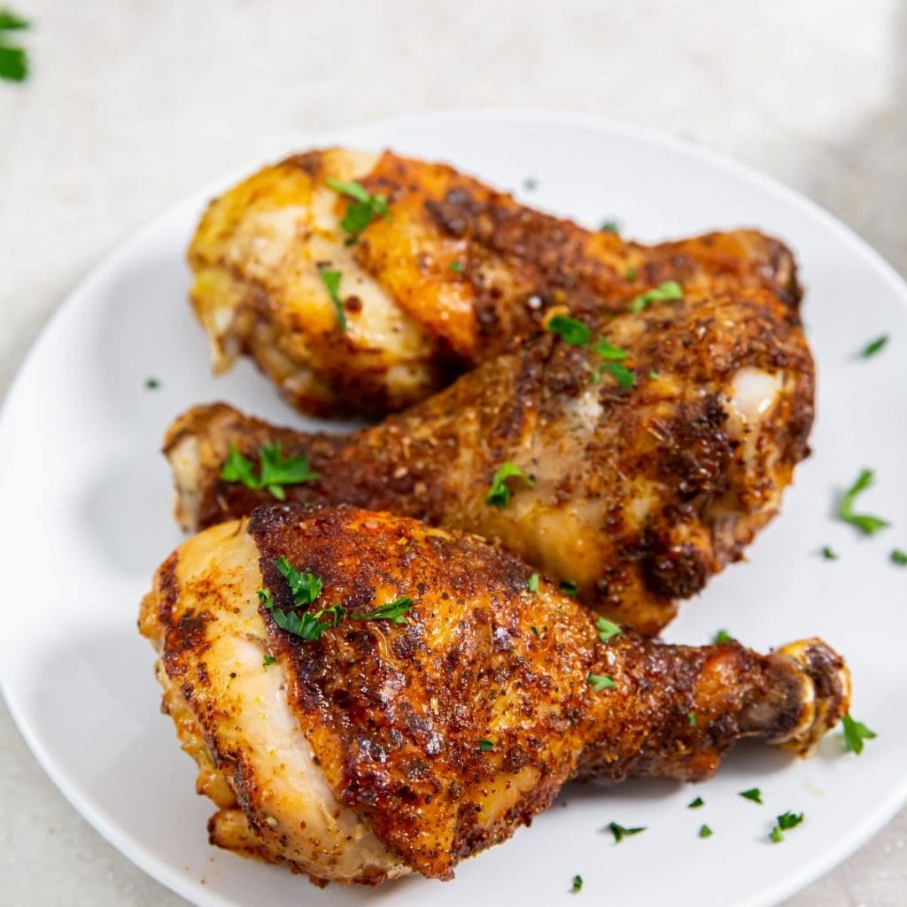 white plate with chicken parsley in the back. bite taken out of chicken